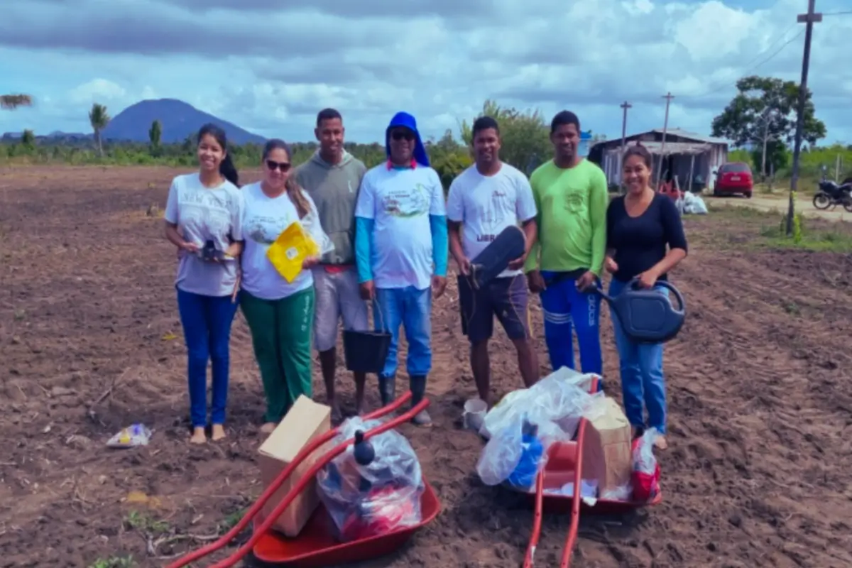 Group of workers posing beside wheelbarrow. 