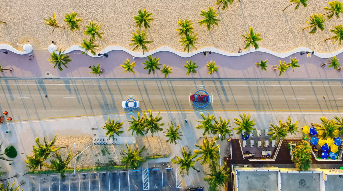 Aerial Drone View: White Autonomous Self Driving Car Moving Through City.