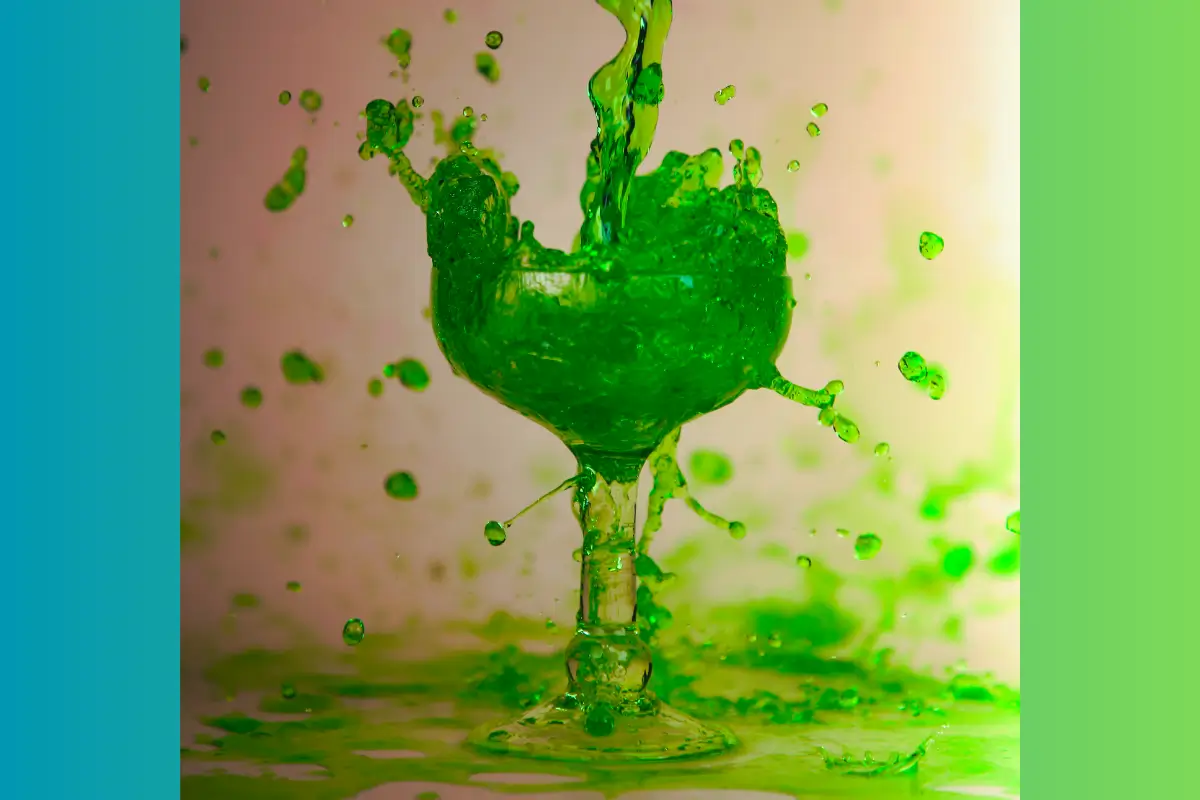 Cup overflowing with green liquid. 